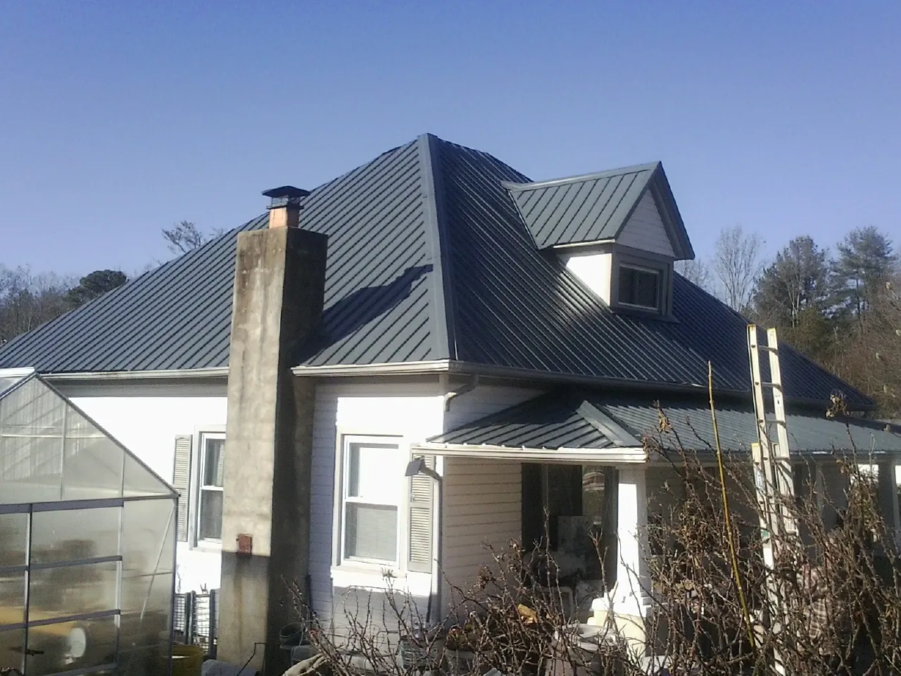 Dark blue standing seam metal roof on a white farmhouse with dormer — Slate & Tile Roof Repair by Roofing Brothers in Snow Shoe