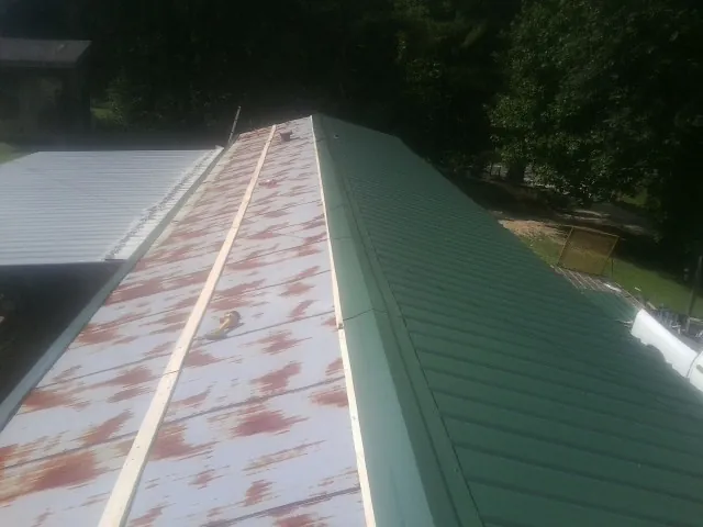 Old rusted panels beside newly installed green metal roofing — Wind Damage Roof Repair by Roofing Brothers in Snow Shoe