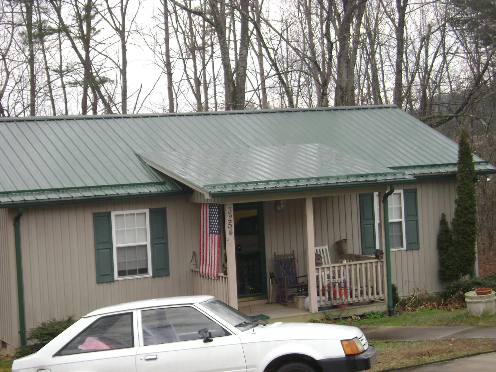 Green metal roof and front porch on a tan sided cottage in Snow Shoe