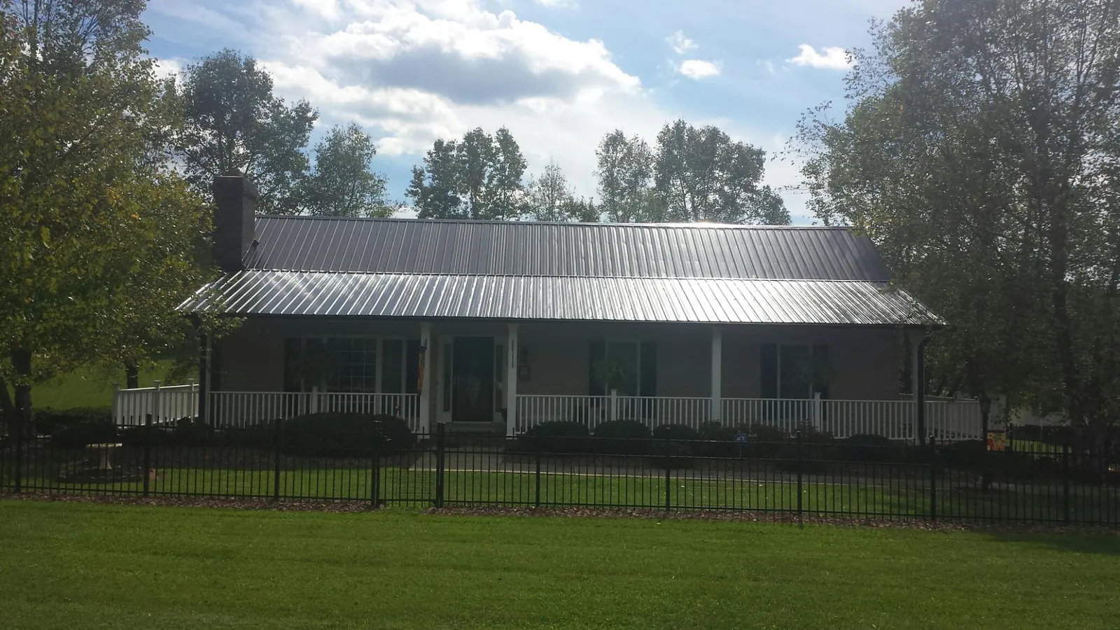 Gray metal roof on a brick ranch with a full width front porch — Gutter Guard Installation work by our crew in Snow Shoe