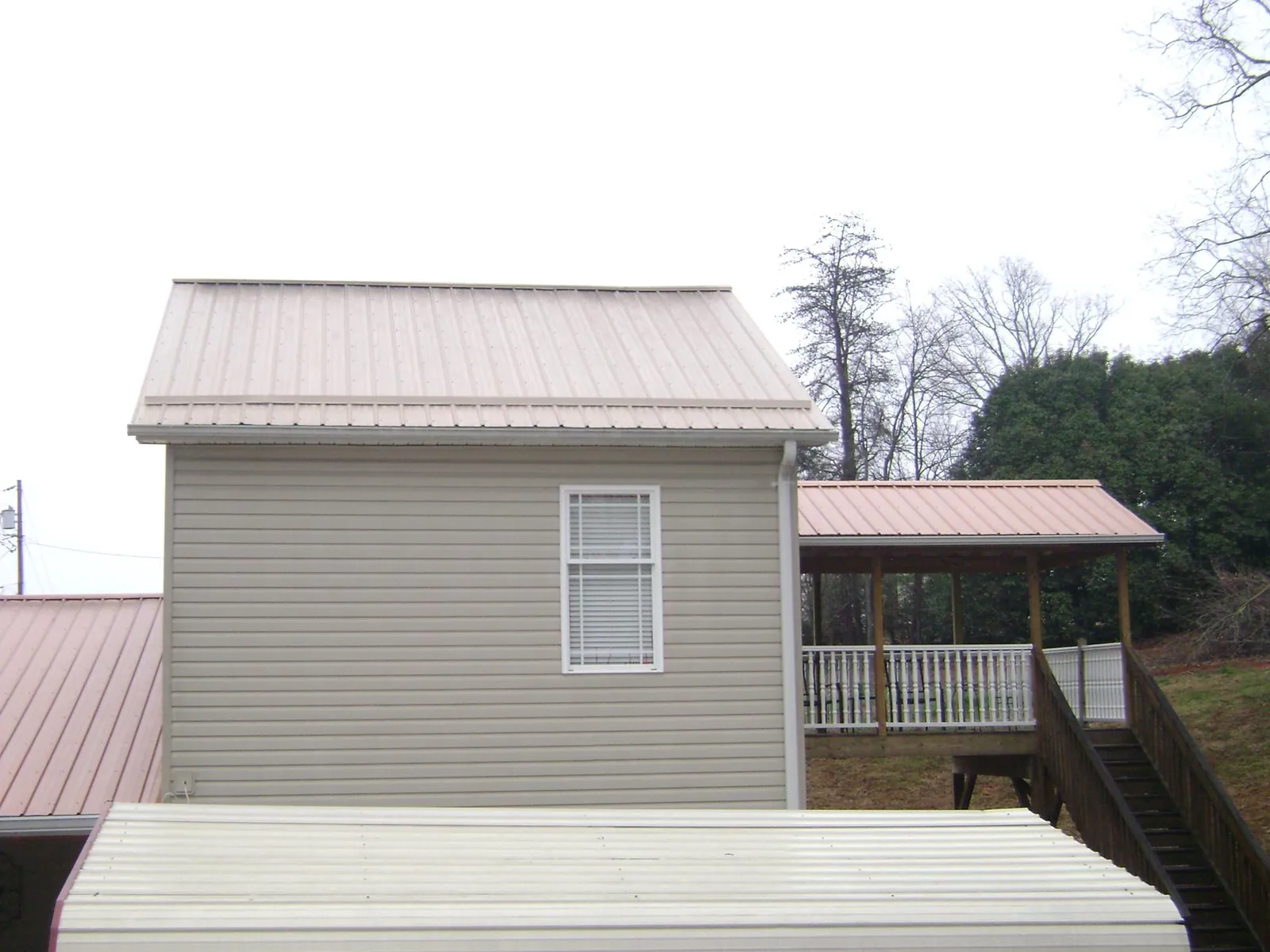 Tan metal roofs on a two story addition and attached porch, from a Roof Replacement job in Snow Shoe