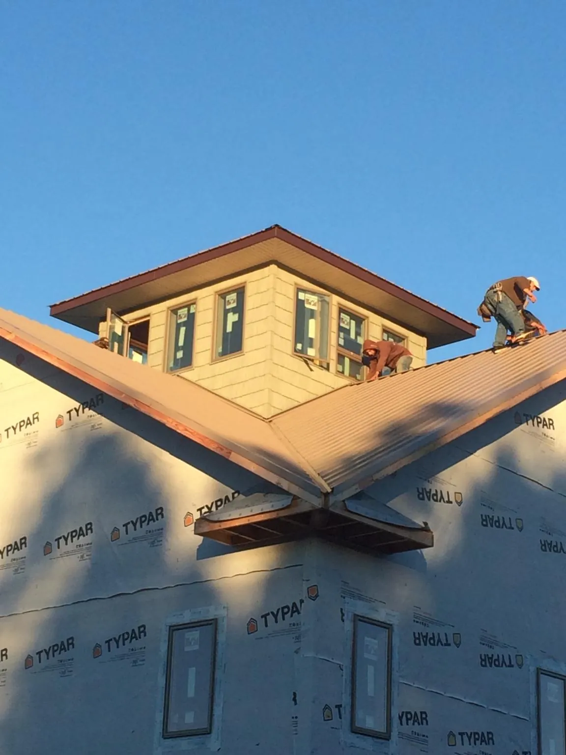 Roofers working around a rooftop cupola on a new metal roof at sunset — Roof Waterproofing in Snow Shoe by Roofing Brothers